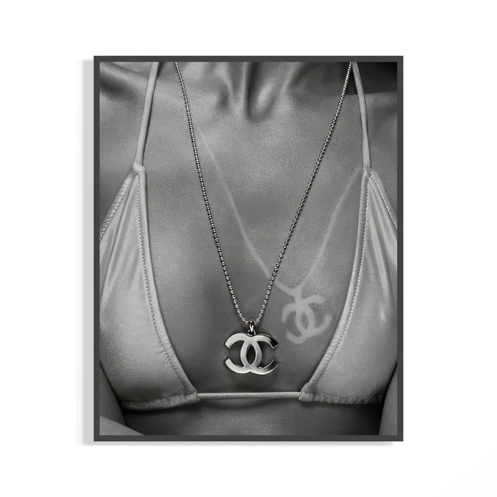 Black and white close-up of a Chanel CC pendant necklace resting over a graffiti-detailed bikini top