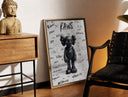 Brass-framed Black KAWS Companion figure standing print leaning in a warm styled corner by a sculpture