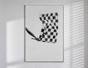 Hand waving checkered racing flag poster in a slim frame on a bright wall with soft window light