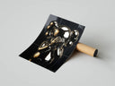 Chrome gold KAWS companion in see-no-evil pose on black marble tile background, print unrolled beside cardboard tube