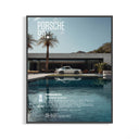 Framed white Porsche 911 poster beside a blue pool with palm tree and mountain backdrop