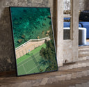 Seaside tennis court by ocean print in a black frame leaning beside a vintage door on parquet