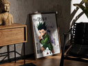 Walnut-framed Gon and Killua anime characters print leaning against a sunlit rustic brick wall