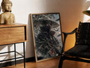 Brass-framed anime ninja with red eyes print leaning in a warm styled corner by a sculpture