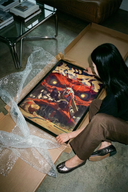 Woman revealing a Jiraiya Toad Sage Naruto wall art poster from protective brown cardboard packaging