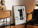 Brass-framed KAWS Companion Passing Through figure print leaning in a warm styled corner by a sculpture