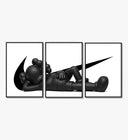 Black stylized figure lying down with crossed eyes three-panel set arranged on a gallery wall