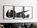 Black stylized figure lying down with crossed eyes three-panel set styled in a living room