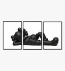 Black stylized cartoon character figures in reclined poses three-panel set arranged on a gallery wall