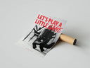Let's Play a Little Game fashion print unrolled beside cardboard shipping tube on gray surface showing full bold red and B&W design