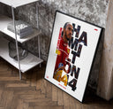 Lewis Hamilton F1 driver portrait poster in a black frame leaning beside a shelf in a raw-plaster loft