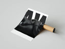 Matte-black KAWS companion lying down with crossed arms against clean white backdrop, rolled print