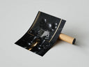 Matte black KAWS companion sitting on gold toilet reading newspaper against black marble, print unrolled beside tube