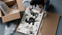 KAWS figure wearing Air Jordan sneakers framed print being unpacked from protective bubble wrap and a box