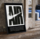Nike Air logo with swoosh print in a black frame leaning beside a vintage door on parquet