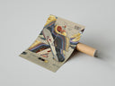 Person unrolling white paper over Nike Air Max 97 Sean Wotherspoon poster showing colorful striped sneaker design on concrete surface