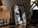 Walnut-framed KAWS Companion figure standing print leaning against a sunlit rustic brick wall