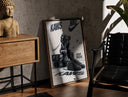 Walnut-framed KAWS Companion figure and sneaker print leaning against a sunlit rustic brick wall