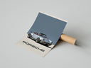 Person carefully unrolling a Porsche 911 Turbo Classic Silver art print with red leather interior on concrete floor
