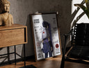 Walnut-framed Sasuke Uchiha standing with sword print leaning against a sunlit rustic brick wall