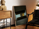 Brass-framed Se7en box scene print leaning in a warm styled corner by a sculpture