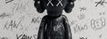KAWS companion against a hand-tagged graffiti wall — best sellers detail
