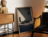 Brass-framed Vintage green Porsche 911 coupe print leaning in a warm styled corner by a sculpture