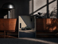 Black-framed Vintage green Porsche 911 coupe print on a moody console with designer coffee-table books