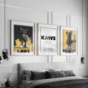 Contemporary Wall Art Set of 3 Posters featuring KAWS-inspired digital prints in black, white, and yellow, framed above a modern bedroom bed — Haus of Prints.