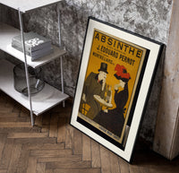 Man and woman drinking absinthe at table poster in a black frame leaning beside a shelf in a raw-plaster loft