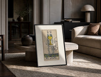 Ace of Cups tarot card print in a black frame leaning on a travertine table in a sunlit lounge