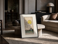 Hand holding pentacle coin print in a black frame leaning on a travertine table in a sunlit lounge