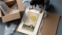 Hand holding pentacle coin framed print being unpacked from protective bubble wrap and a box