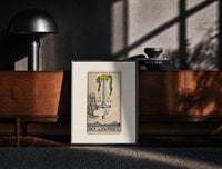 Black-framed Hand holding upright sword with crown print on a moody console with designer coffee-table books