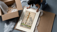 Hand holding sprouting wooden wand framed print being unpacked from protective bubble wrap and a box