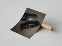 Velvet Brown Dark Mocha sneaker poster leaning beside a cardboard shipping tube on a gray surface