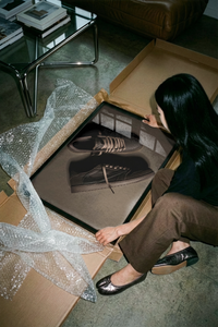 Unrolling the Travis Scott Velvet Brown Mocha sneaker print on a concrete floor before hanging