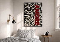Amore Zebra Print in a black frame above a bed with striped linens, a brass wall lamp and a sunlit window