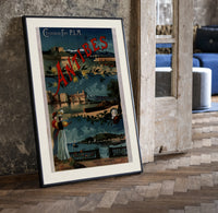 Antibes coastal town scene print in a black frame leaning beside a vintage door on parquet