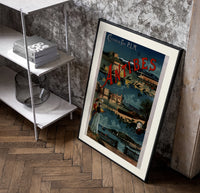 Antibes coastal town scene poster in a black frame leaning beside a shelf in a raw-plaster loft