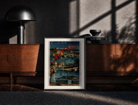Black-framed Antibes coastal town scene print on a moody console with designer coffee-table books