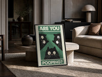 Are You Pooping Three Cats print on the floor, leaning against a travertine table