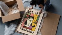 Are You Pooping Tuxedo Cat framed print being unpacked from protective bubble wrap and a box