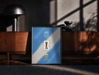Black-framed FIFA World Cup 2026 Argentina logo print on a moody console with designer coffee-table books