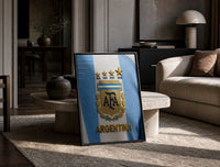 Argentina football national team crest jersey print in a black frame leaning on a travertine table in a sunlit lounge