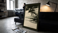 Ghostly figure flying over landscape print in a slim black frame leaning on a dark sofa in a concrete print studio