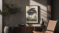 Great blue heron bird poster framed above a fluted sideboard beside an olive tree