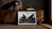 Two peregrine falcons with prey print in a black frame leaning against a walnut console in lamplight