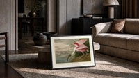 Roseate spoonbill wading bird print in a slim black frame leaning on a travertine coffee table