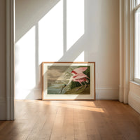 Roseate spoonbill wading bird print in an oak frame on a sunlit wood floor beneath tall window light
